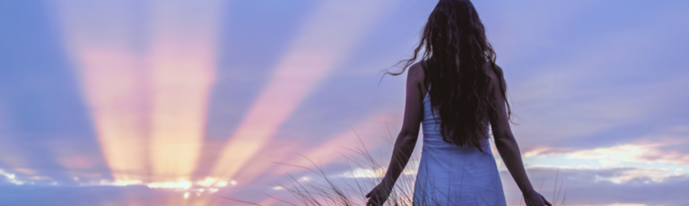 Femme sereine contemplant l'horizon au lever du soleil, symbolisant le choix du cœur et la libération vers un futur aligné